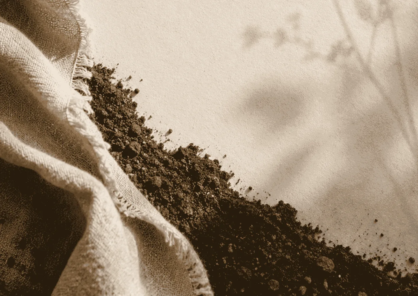 re:turn project visual: undyed cloth lying in soft folds on bare earth.