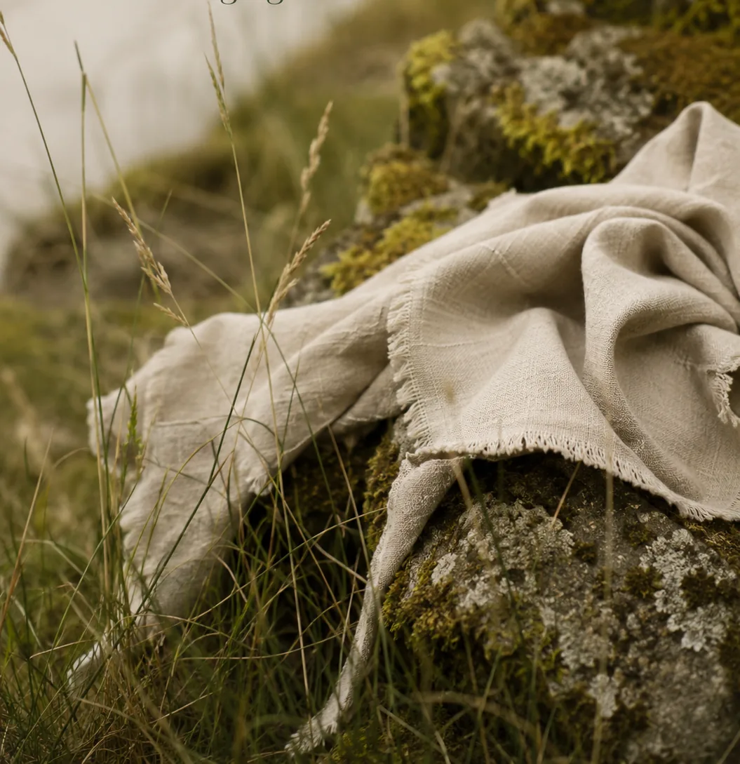 re:turn project visual: undyed cloth draped over a mossy stone in long grass.
